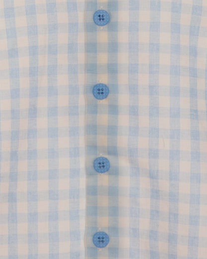 Closeup of light blue and white checkered shirt and blue buttons.