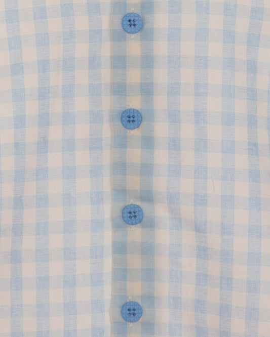 Closeup of light blue and white checkered shirt and blue buttons.