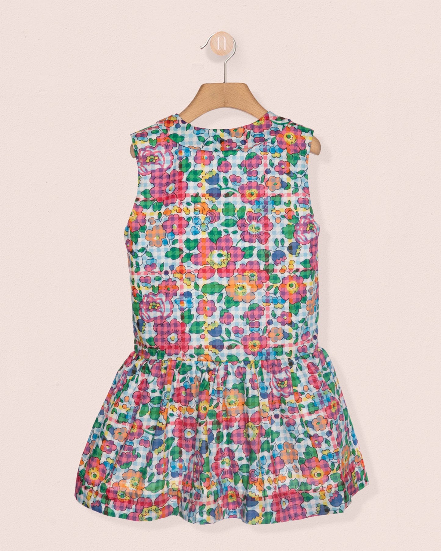 Colorful floral dress on a hanger against a beige background