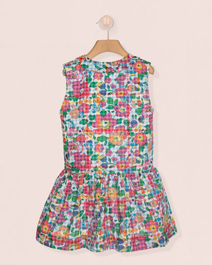 Colorful floral dress on a hanger against a beige background