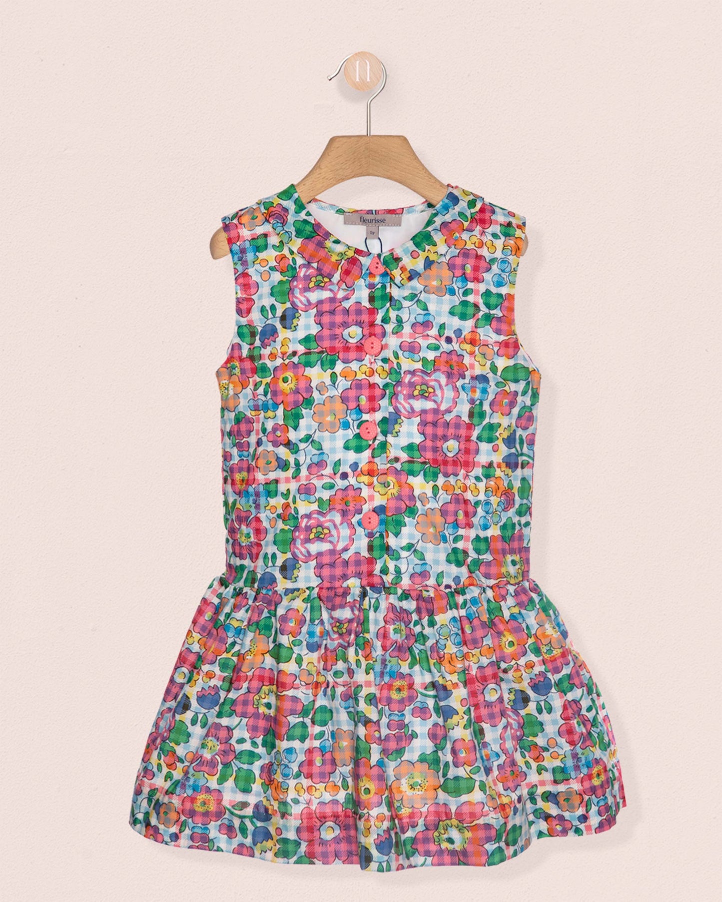 Colorful floral dress on a hanger against a beige background