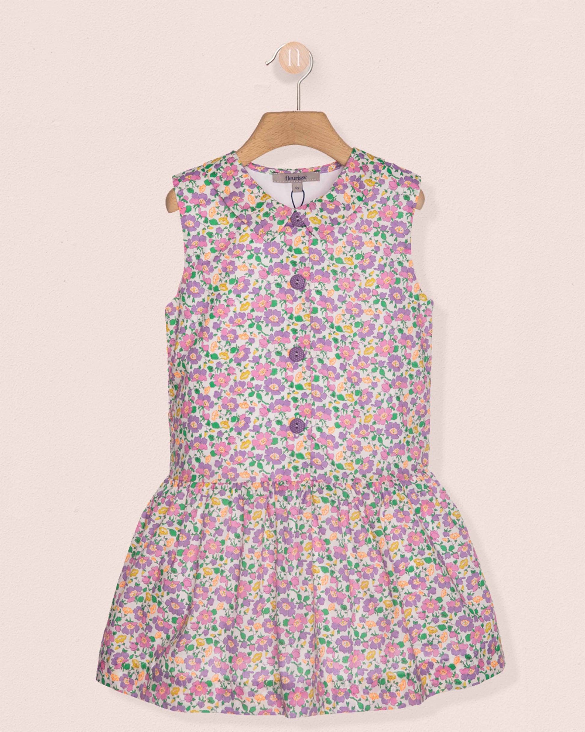 Floral dress on a hanger against a light pink background
