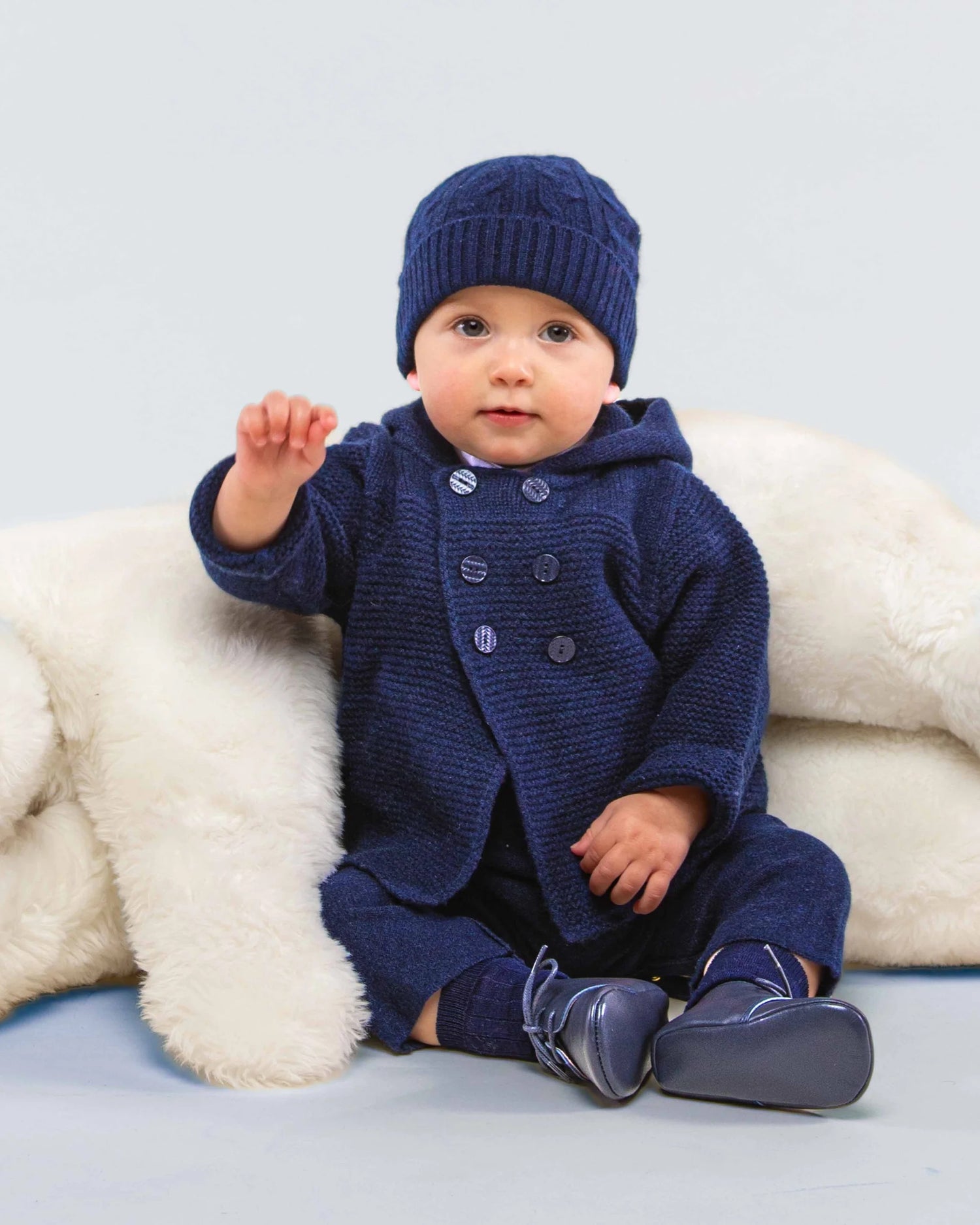 Baby wearing a navy blue outfit with a matching hat on a light background