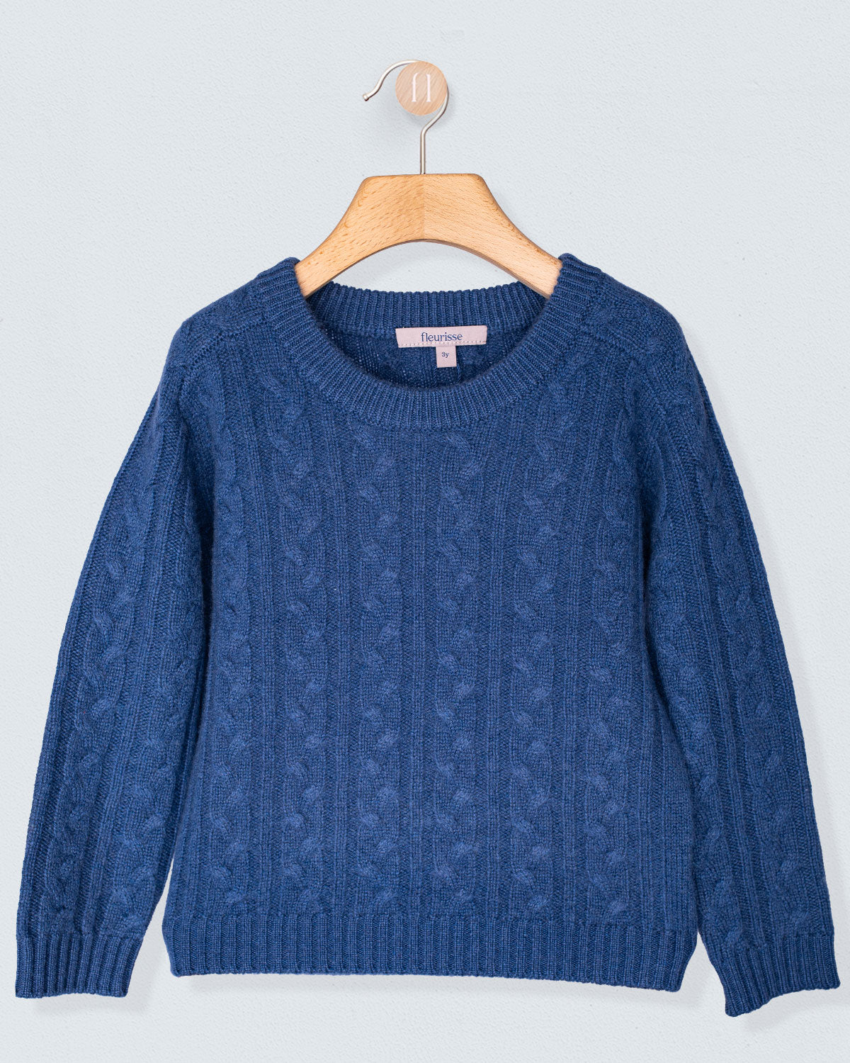 Blue sweater on a wooden hanger against a light gray background