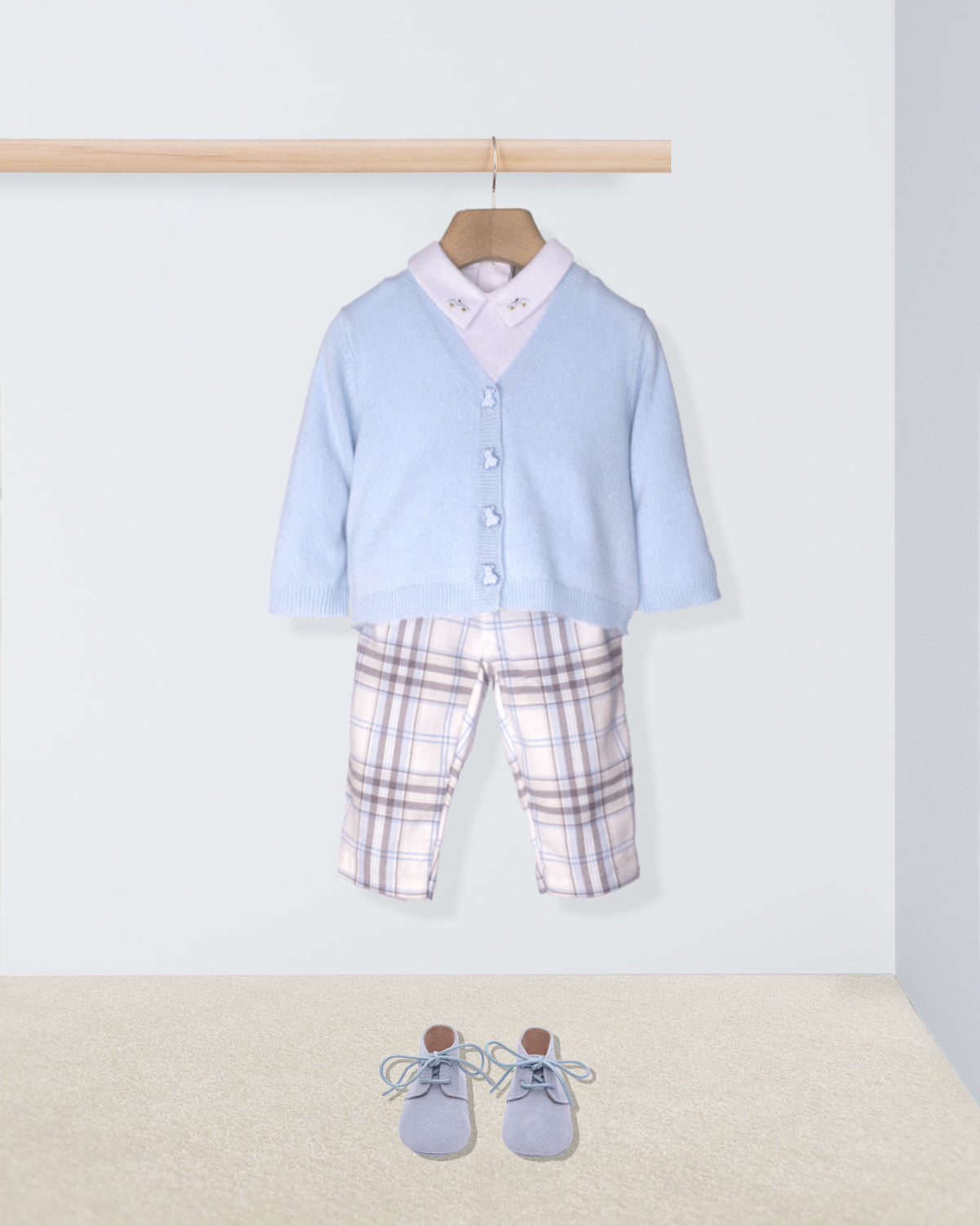 Children's outfit with light blue cardigan, plaid pants, and shoes on a white background