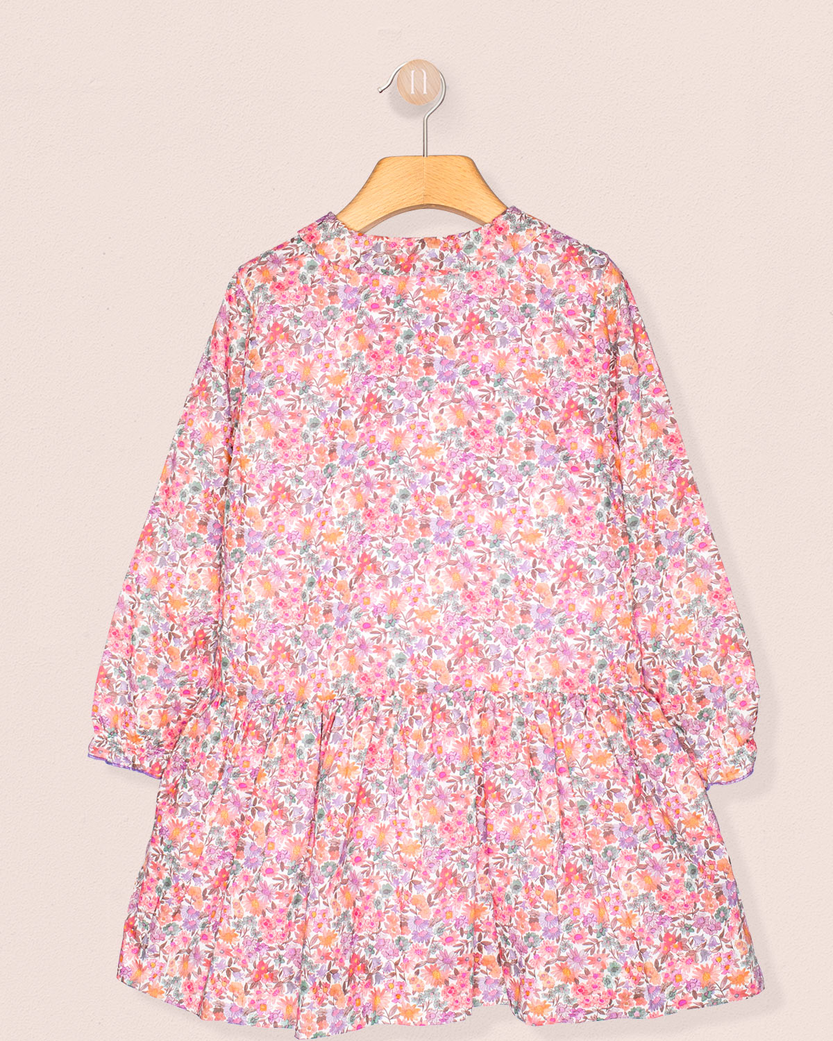 Floral dress on a hanger against a beige background back view