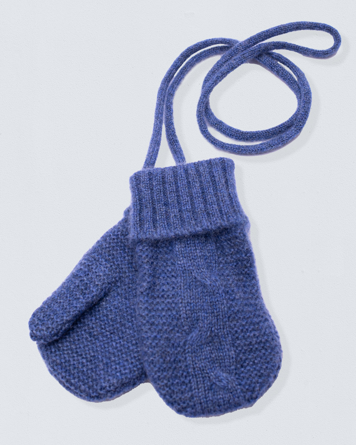 Blue knitted mitten with a strap on a light gray background