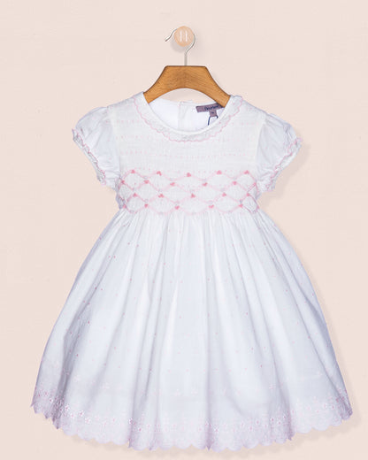 White dress with pink floral embroidery on a beige background