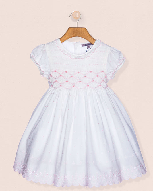 White dress with pink floral embroidery on a beige background