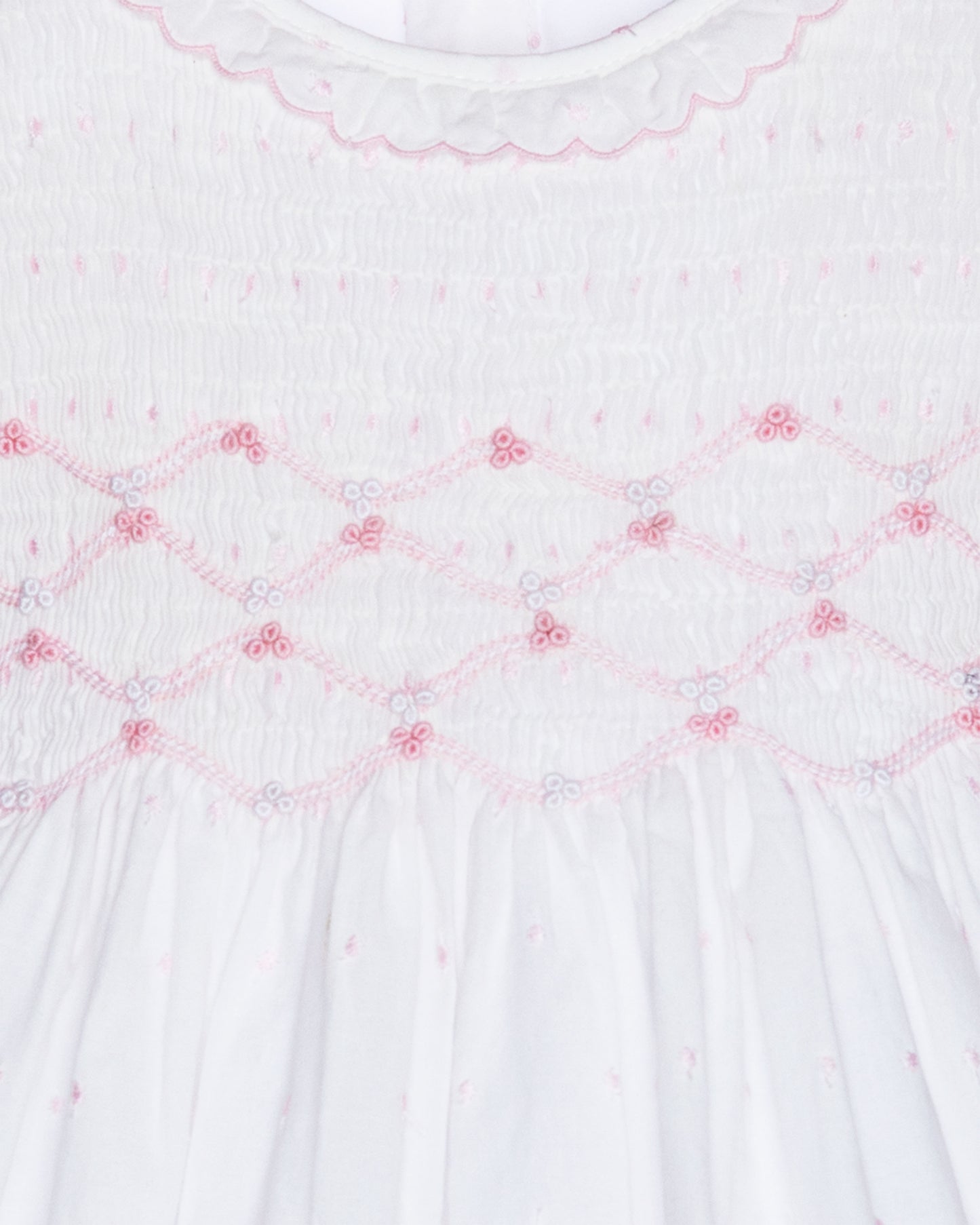 Close-up of a white fabric with pink embroidery patterns