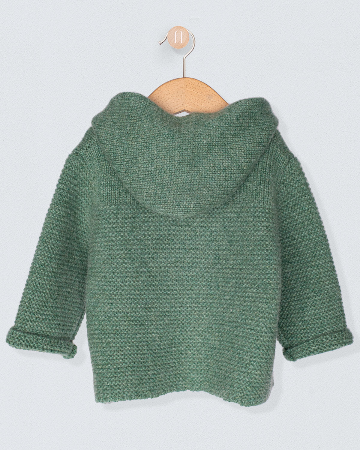 Back of Green knitted jacket on a wooden hanger against a light gray background
