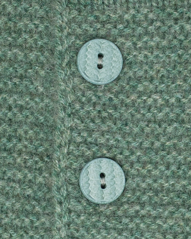 Sweater close-up of two buttons on a textured green fabric background