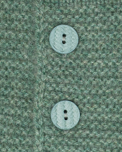 Sweater close-up of two buttons on a textured green fabric background
