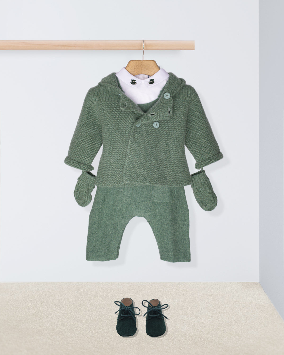 Green baby outfit with matching mittens and shoes on a white background