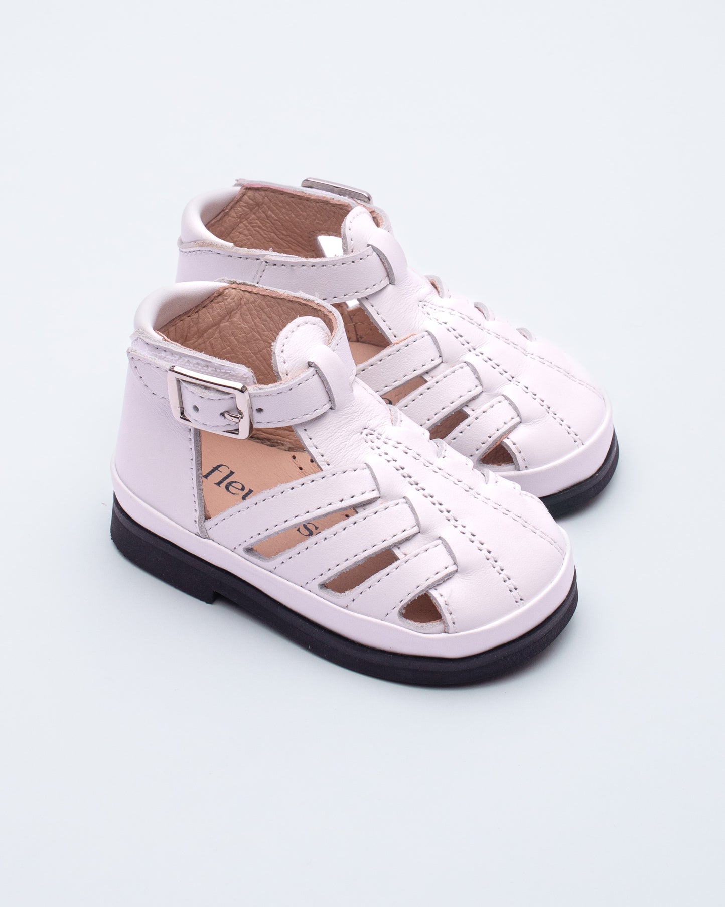 Pair of whitechildren's sandals on a light gray background