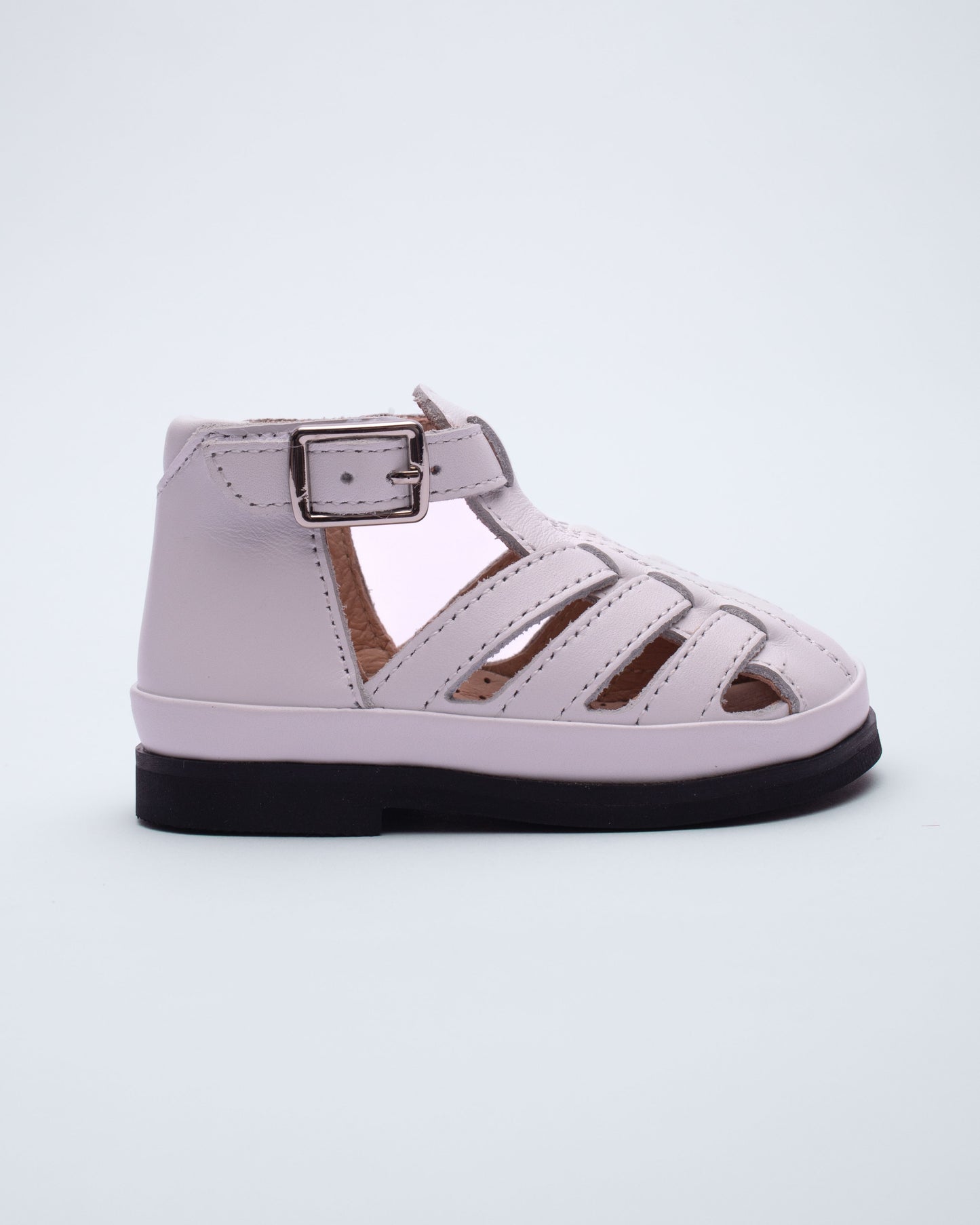 white sandal with a black sole on a light gray background