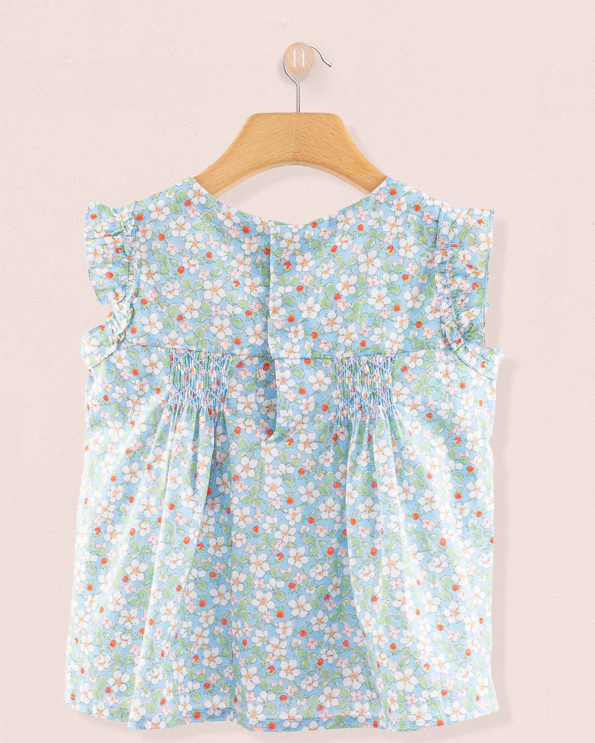 Back view of the Amelie Liberty Strawberry Field Blue Tunic featuring ruffle details and a hidden snap opening along the back in a pale blue floral Liberty print.