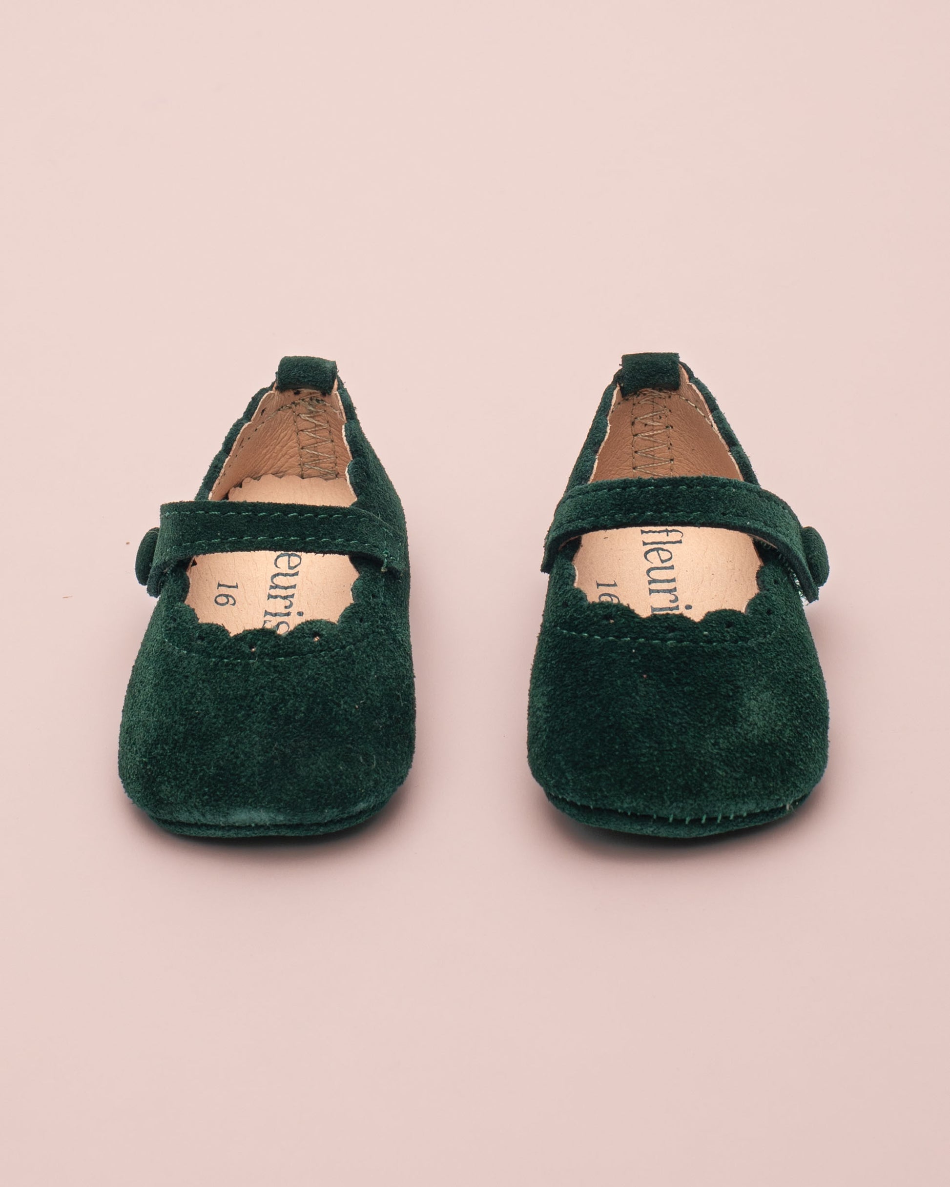 Pair of green children's shoes on a pink background