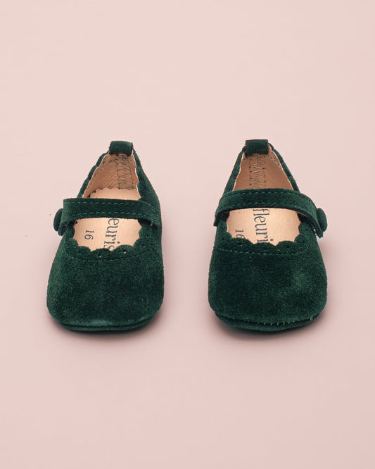 Pair of green children's shoes on a pink background