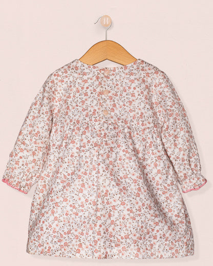 Floral dress on a wooden hanger against a light pink background