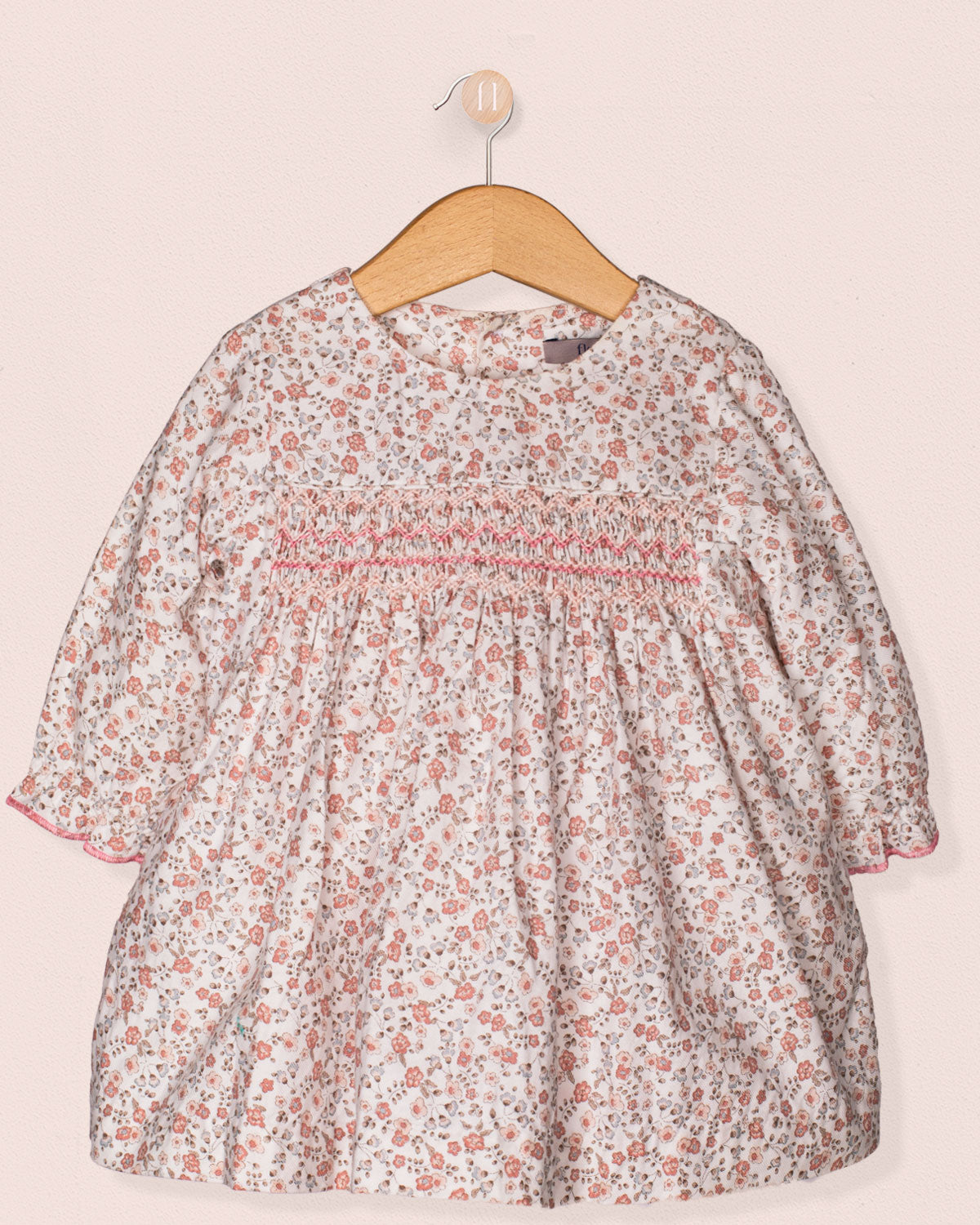 Floral dress on a hanger against a light pink background