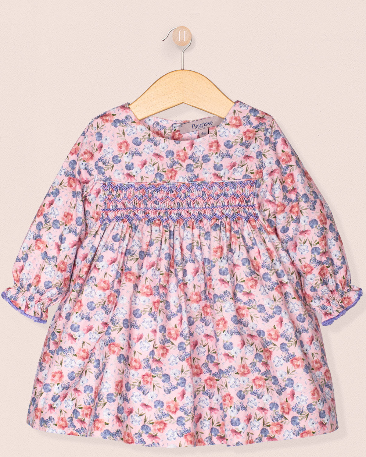 Floral dress on a hanger against a beige background