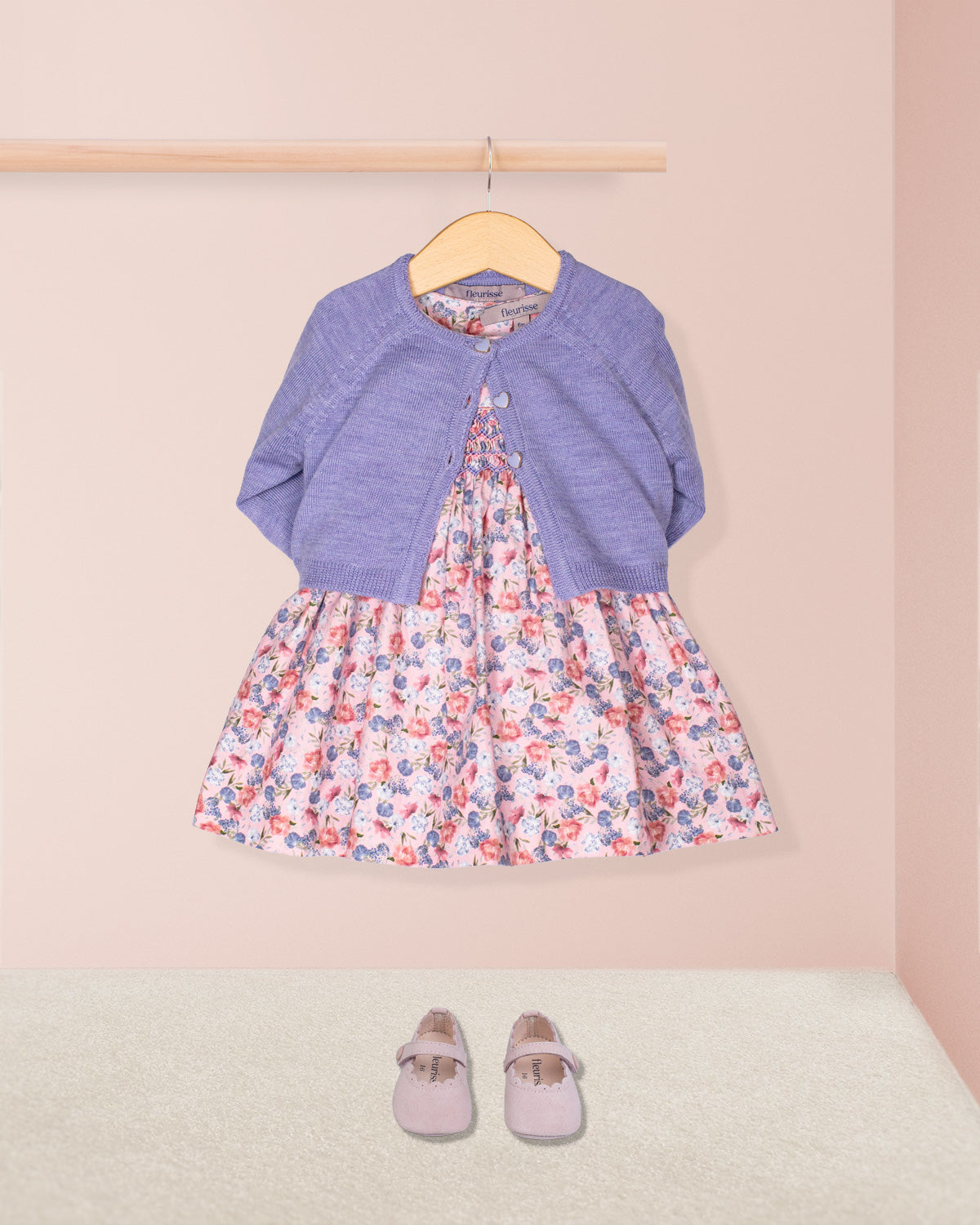 Floral dress with a blue cardigan and shoes on a pink background