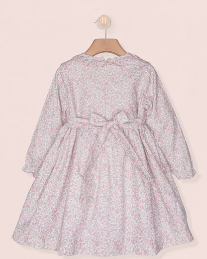 Floral dress on a hanger against a light pink background