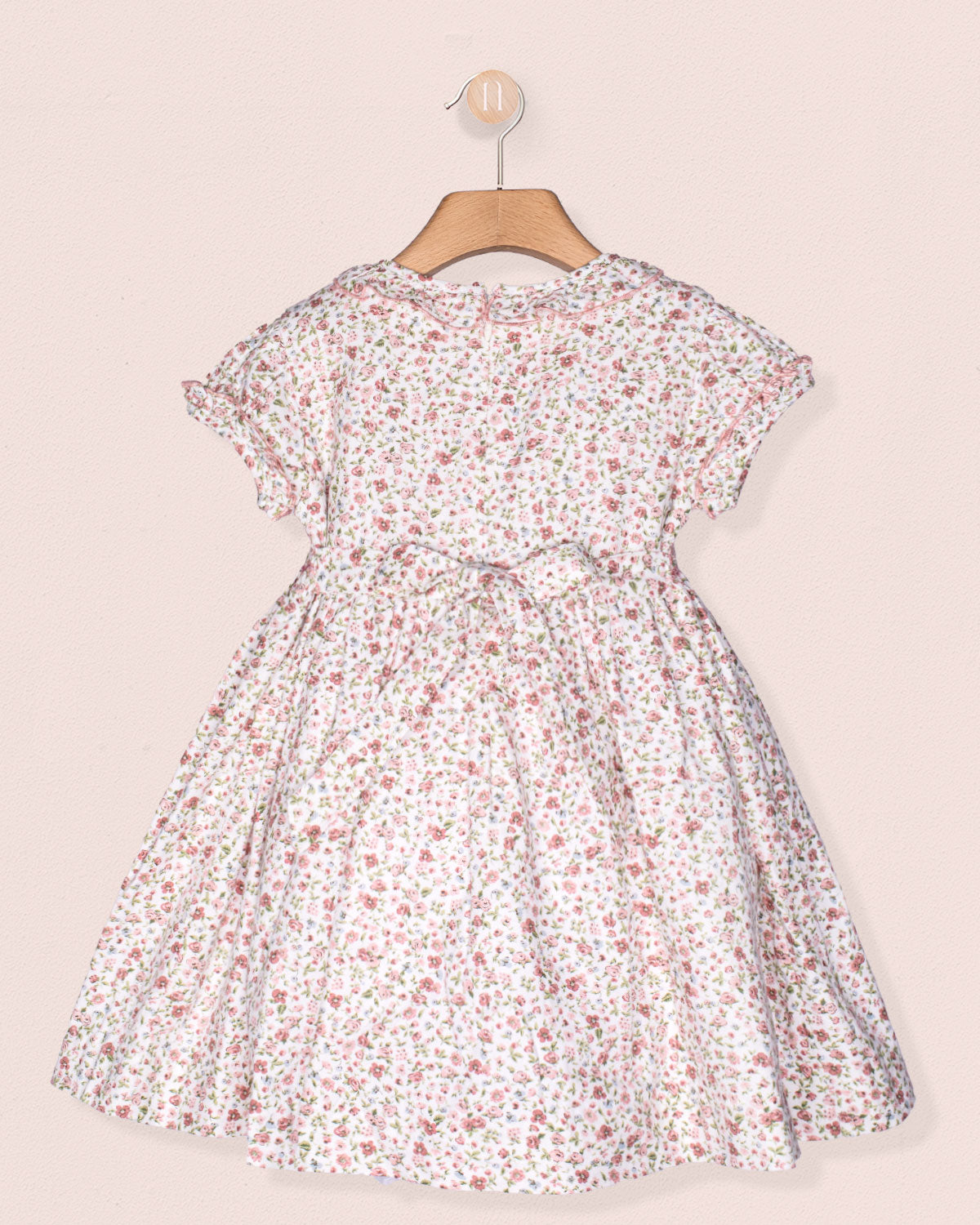 Floral dress on a hanger against a light pink background