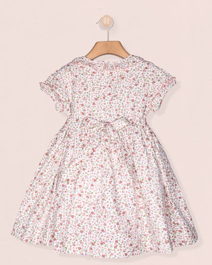 Floral dress on a hanger against a light pink background