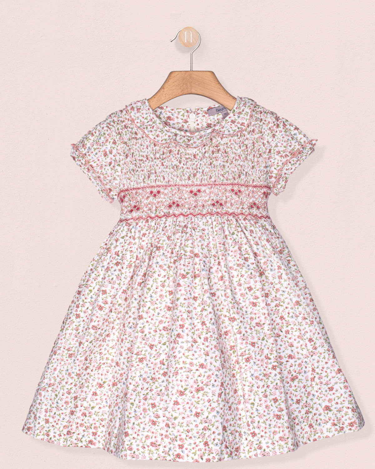 Floral dress on a hanger against a light pink background