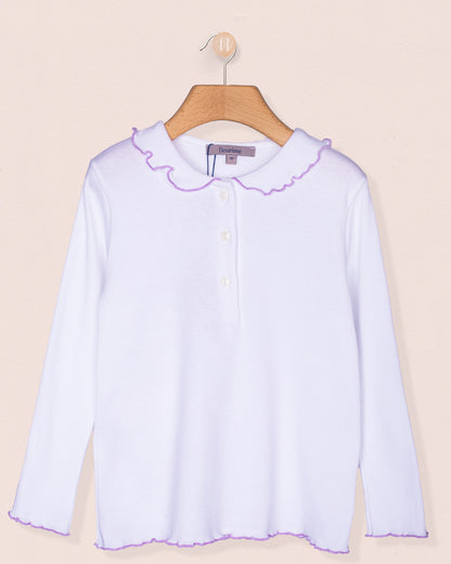 Long sleeve white brushed cotton shirt for girls displayed on a wooden hanger against a pale pink background. Features a rounded ruffle collar and hemline with lavender scalloped trim and star-shaped buttons down the front.