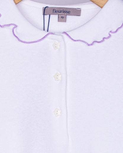 Close-up view of the soft brushed cotton fabric on the white long sleeve shirt, showing the delicate ruffle collar with lavender trim and three small white star-shaped buttons on the front placket.