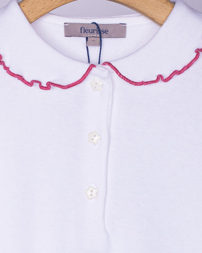 Close-up view of the soft brushed cotton fabric on the white long sleeve shirt, showing the delicate ruffle collar with rose-pink trim and three small white star-shaped buttons on the front placket.