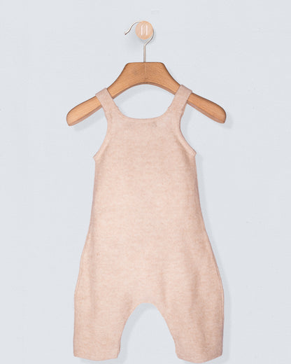 Pink baby romper on a wooden hanger against a light gray background