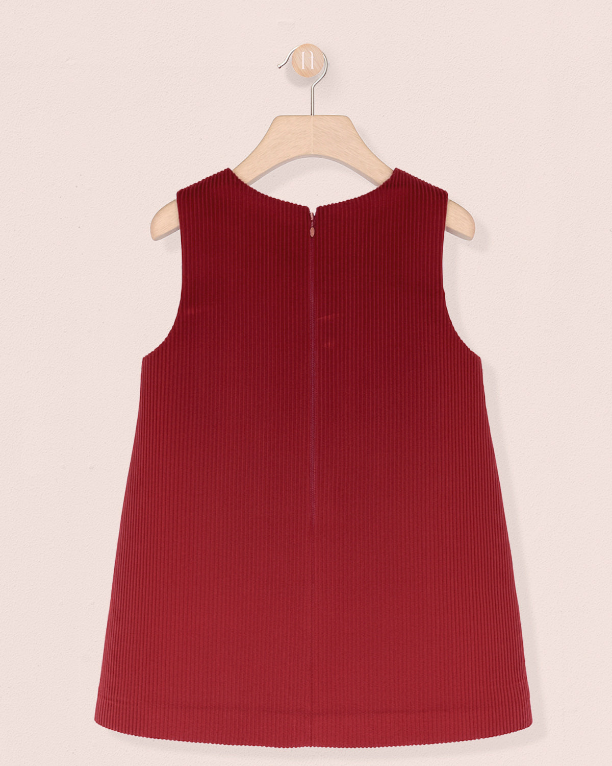 back of Red sleeveless dress on a hanger against a light pink background