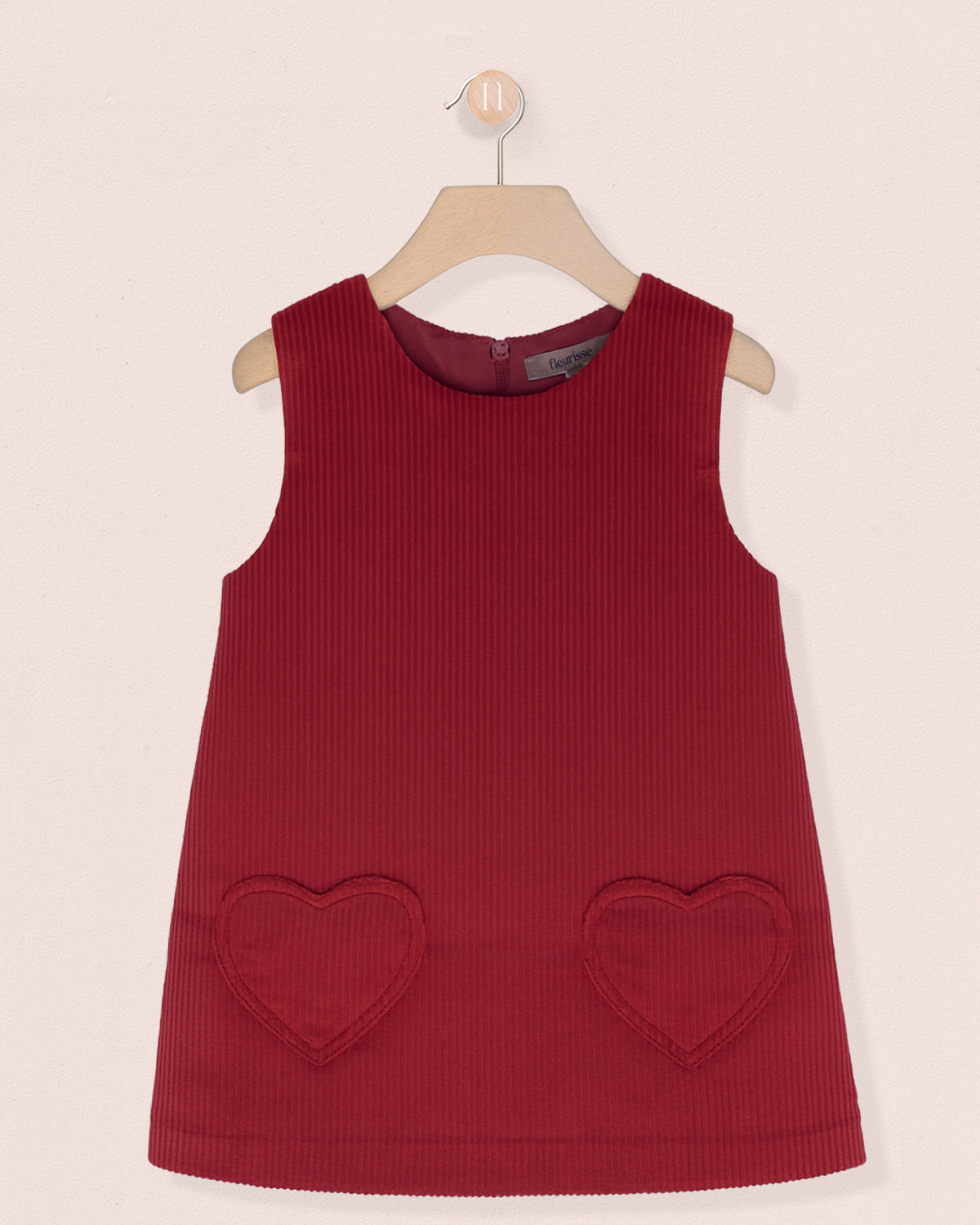 Red sleeveless dress with heart-shaped pockets on a beige background