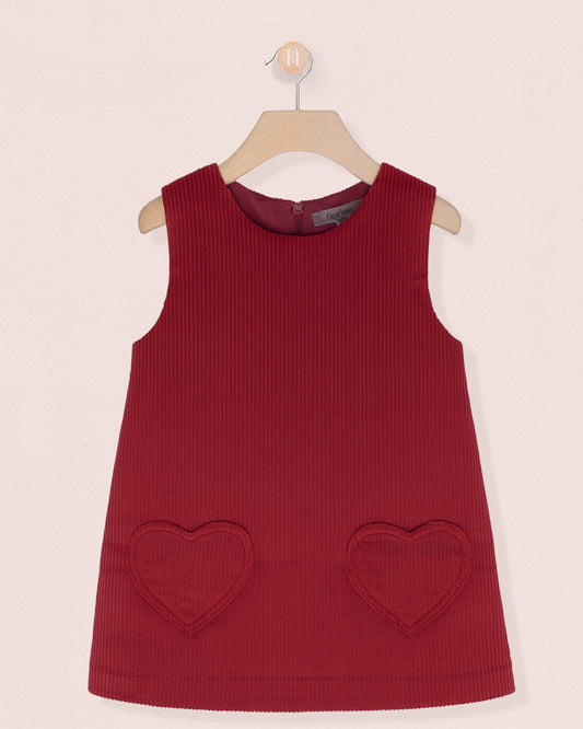 Red sleeveless dress with heart-shaped pockets on a beige background