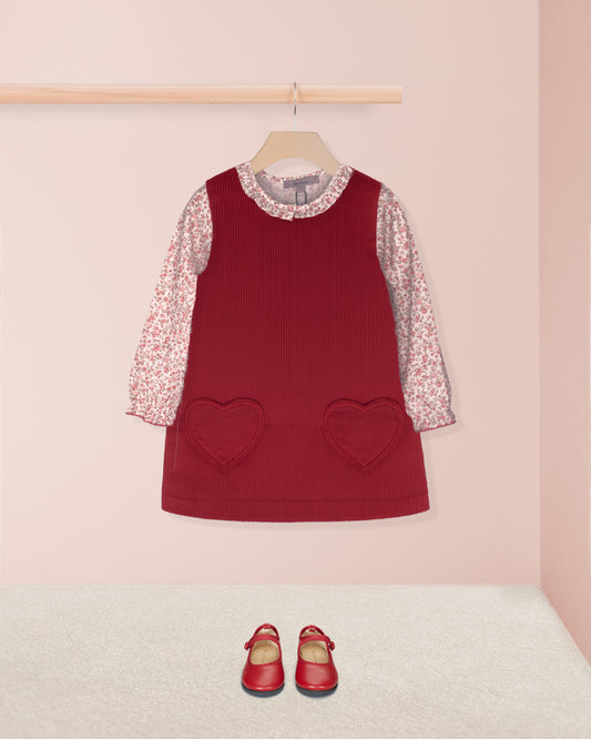 Red dress with floral sleeves and heart pockets on a pink background