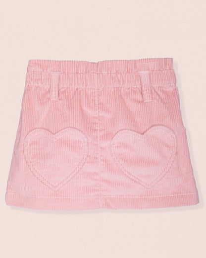 Pink corduroy skirt with heart shaped pockets on a light pink background