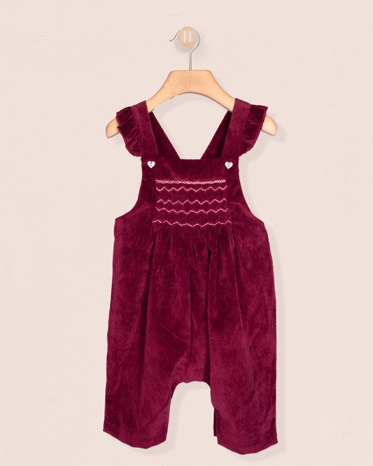 Burgundy velvet romper with ruffled straps on a beige background