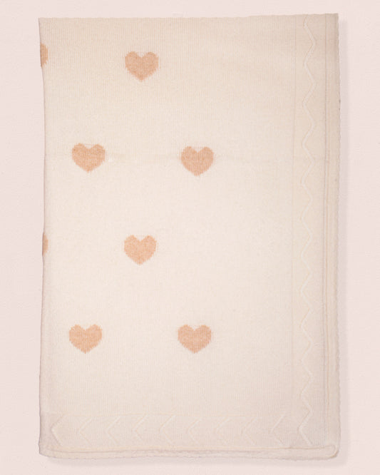 Beige blanket with pink heart patterns on a light pink background