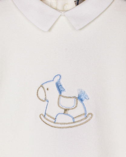 Close-up of embroidered blue rocking horse on plush off-white velour fabric, with classic Peter Pan collar detail visible.