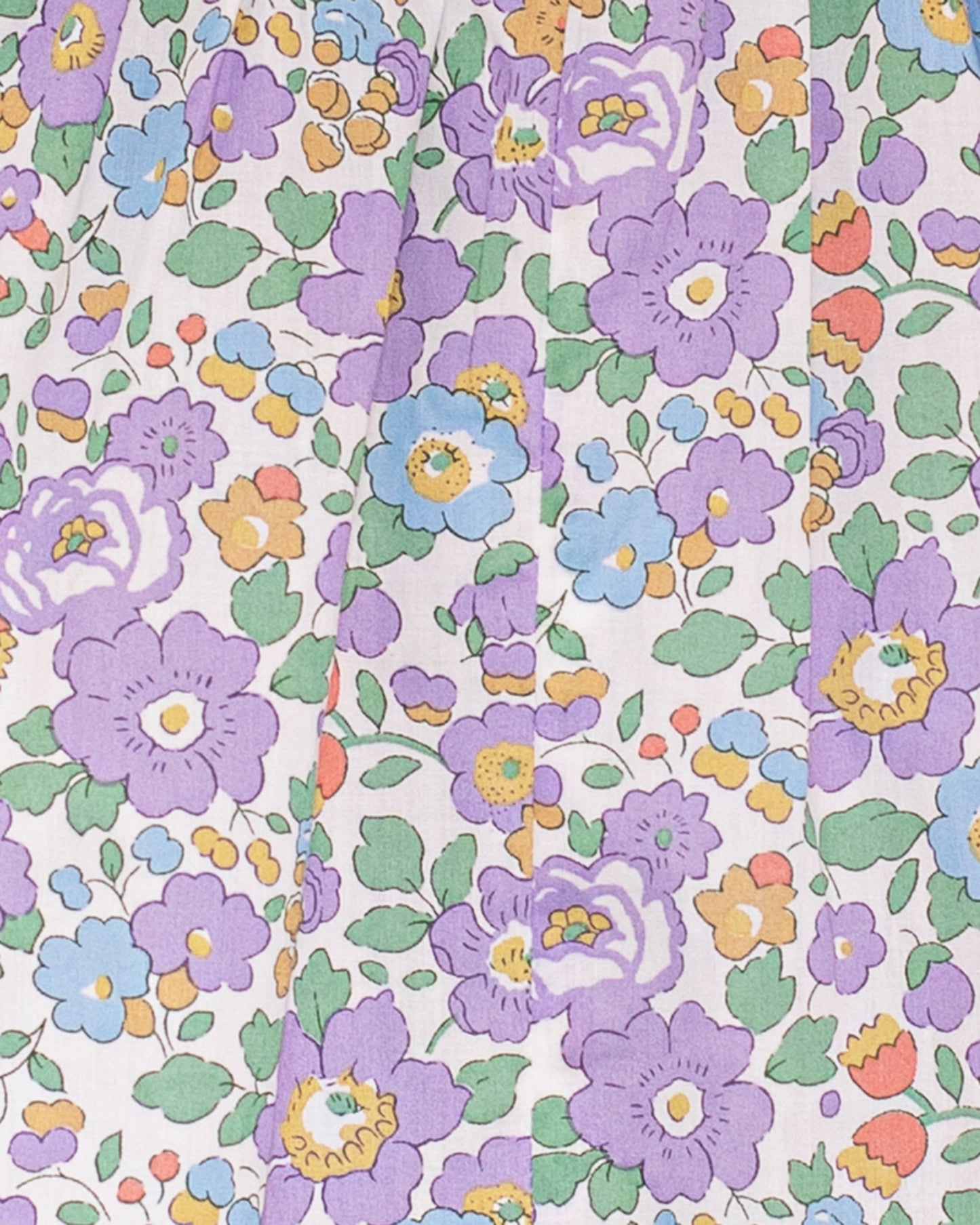 Close-up of the Amandine Liberty Betsy Lavender Smock fabric, featuring a detailed Liberty of London floral print in lavender, green, orange, blue, and white.