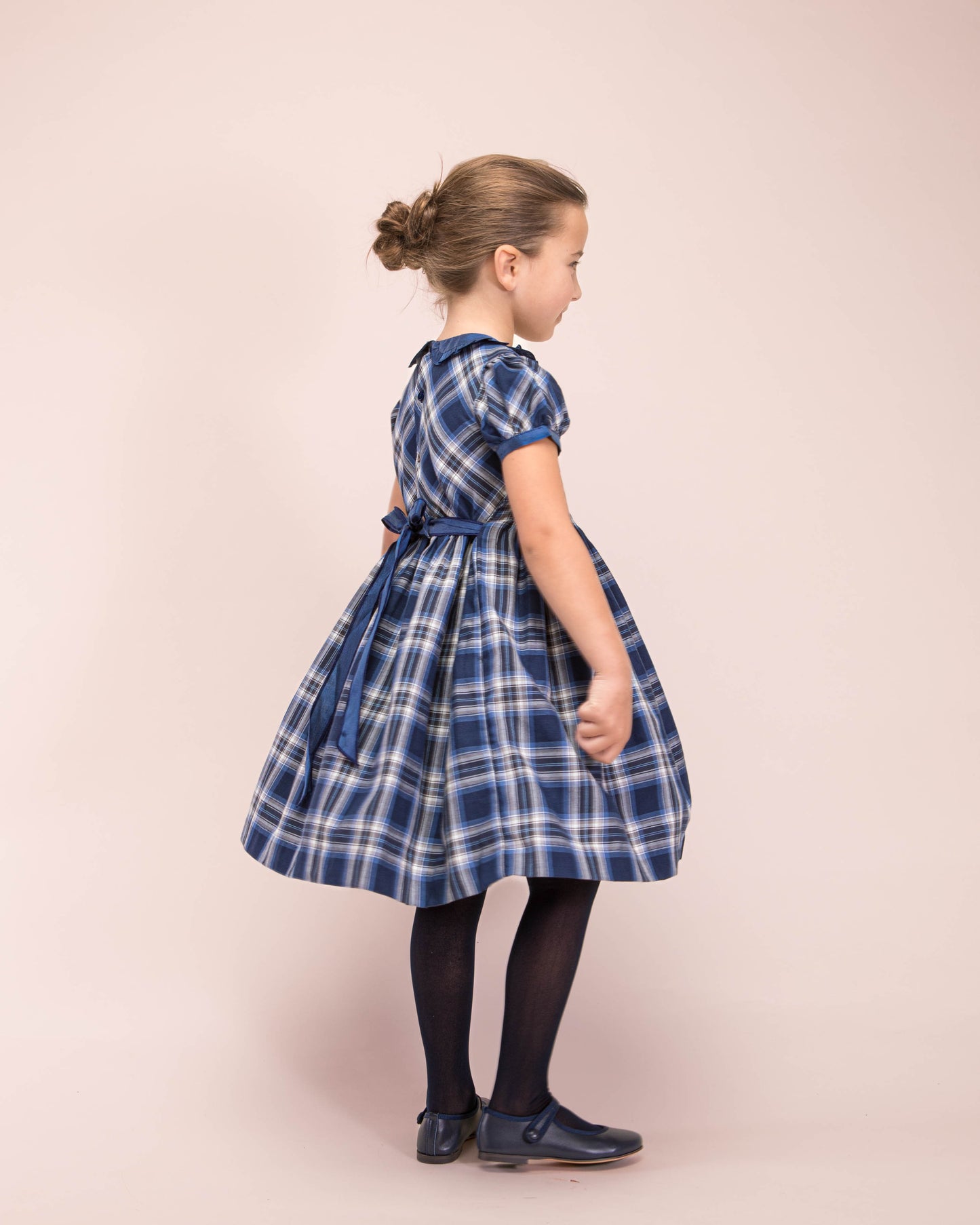 Girl model wearing Victoria Italian Navy Tartan Dress facing sideways to the side and the back of the dress 