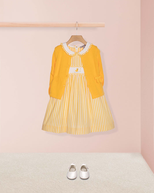 Yellow dress with white collar and striped skirt on a hanger against a pink wall.