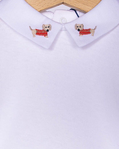 Close-up of embroidered dachshunds wearing maple-colored sweaters on the collar of a white baby onesie made from Italian cotton.