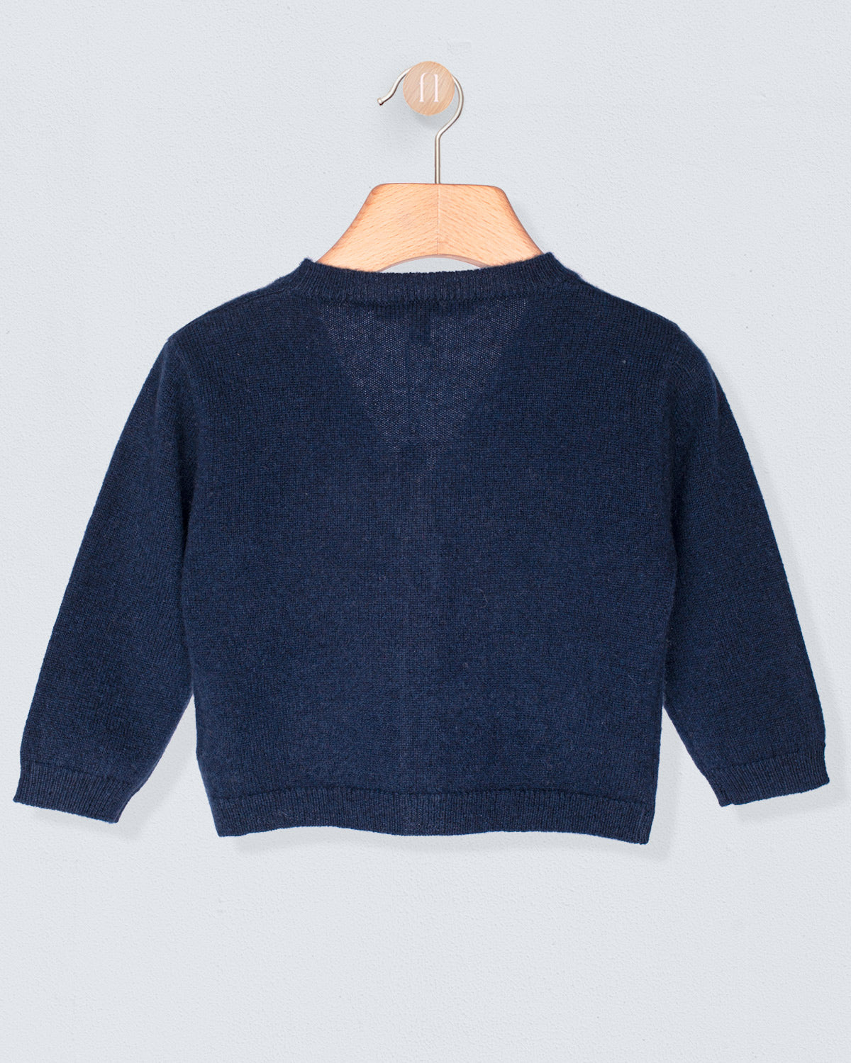 Back of navy blue sweater on a wooden hanger against a light gray background