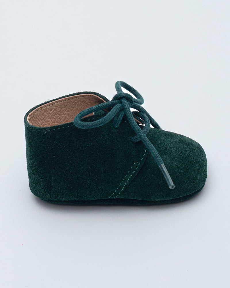 Green baby shoe with laces on a white background