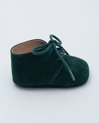 Green baby shoe with laces on a white background